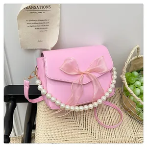 Detailansicht der rosa PU-Lederhandtasche mit großer Organzaschleife und Perlenkette