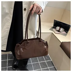 Detail of a dark brown glossy patent leather shoulder bag with double straps and sleek texture