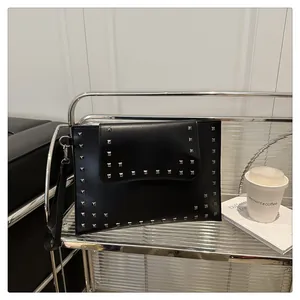 Detailed close-up of a black leather envelope clutch with silver square metal studs