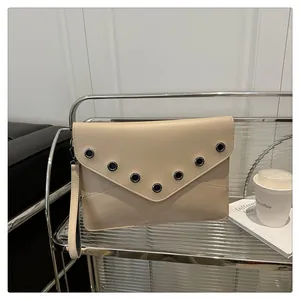 Detail of beige leather envelope clutch with metallic eyelets on the V-shaped flap