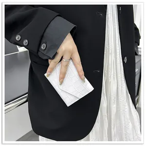 Detail shot of a white crocodile embossed envelope card holder held by a model