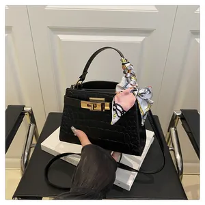 Detail of black faux crocodile texture square bag with gold twist lock and printed silk scarf