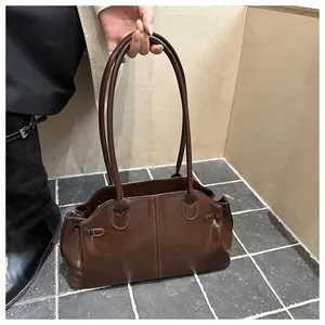 Detail of vintage brown leather shoulder bag with decorative stitching and side buckle strap