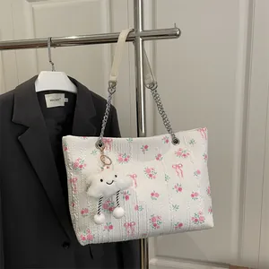 Floral bucket tote bag with rose prints, silver chain strap, and plush charm detail