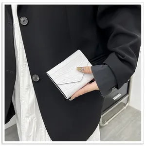 Detail shot of a white faux crocodile skin envelope card holder and refined texture