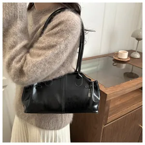 Close-up of black glossy pillow bag with vintage texture and sleek metallic finish