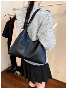 Side view of large black leather hobo bag worn by a model in a warm boutique interior