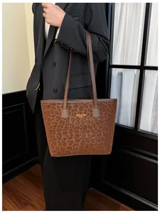 Détail d'un sac cabas à imprimé léopard marron avec lettrage doré New York porté