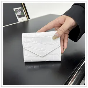 Detail shot of white crocodile embossed envelope mini wallet in patent faux leather