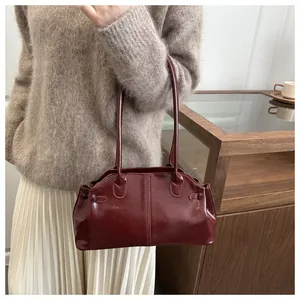 Close-up of a burgundy leather shoulder bag styled with a beige knit sweater for daily commute