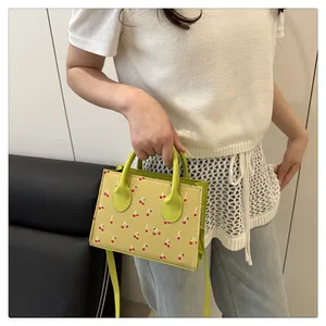 Detail van trendy mini-handtas met kersenprint, textuur en verstelbare schouderband