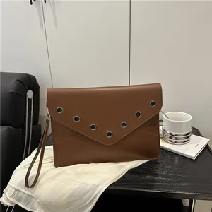 Brown leather envelope clutch bag with silver eyelet studs and a wristlet strap