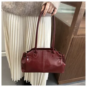 Close-up of wine red faux leather handbag with side pleats and slim double straps