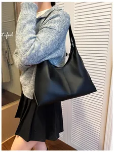 Side view of a large black leather hobo tote bag worn by a model for daily commuting