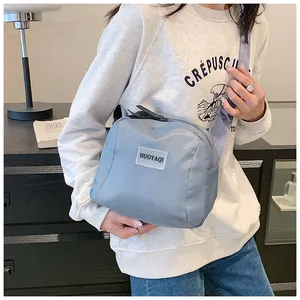 Light blue nylon crossbody bag shown worn by a model in a casual indoor setting