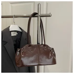 Detail of dark brown glossy patent leather shoulder bag with vertical stitching and thin strap