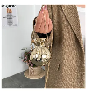 Dettaglio di una mini borsa da sera dorata con design a pieghe e tracolla a catena d'oro