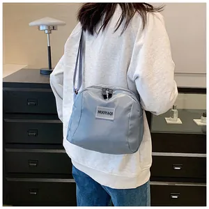 Gray-blue nylon cosmetic bag shown as a shoulder bag on a model in a modern interior