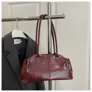 Detail of dark red patent leather shoulder bag hung with a sleek grey blazer