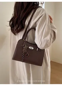 Retro dark brown pebbled leather handbag with silver twist lock on beige trench coat