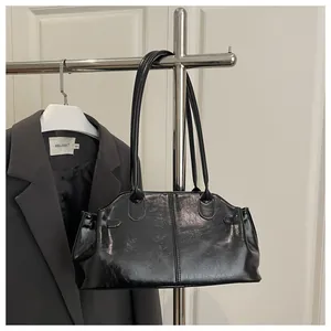 Detail shot of black glossy PU leather shoulder bag featuring vertical stitching and buckles
