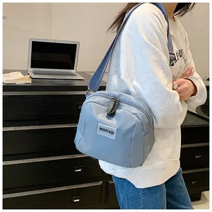 Close-up of a blue crossbody bag with double zipper and adjustable strap on a model