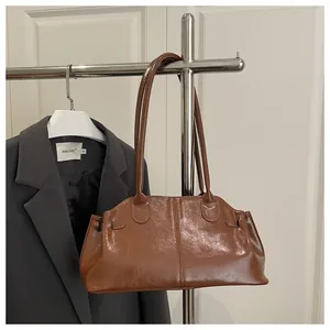 Detail of brown faux leather shoulder bag with glossy finish and vertical stitching