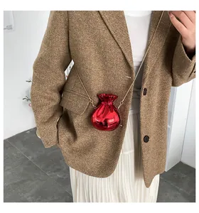Dettaglio mini borsa rossa lucida con catena dorata indossata da una modella