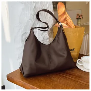 Detail shot of a dark brown large tote bag with visible stitching and silver metal buckle