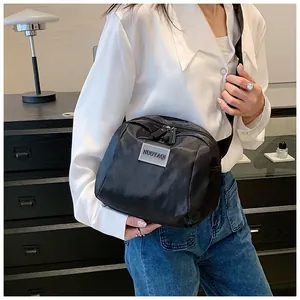 Close-up of black nylon crossbody bag with silver logo and wide shoulder strap detail