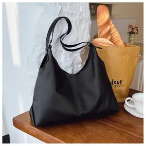 Close-up of a large black minimalist hobo bag placed on a wooden table for daily commute