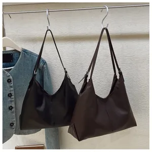 Detail of minimalist leather tote bag showing smooth matte texture and vertical stitching