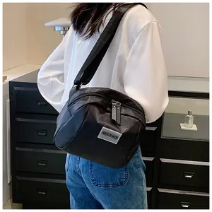 Close-up of a black nylon crossbody bag with dual zippers and adjustable wide strap
