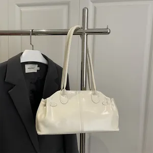 Minimalist cream glossy leather tote bag with double straps hung on a sleek metal hanger