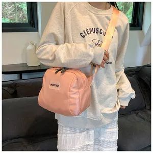 Close-up of peach pink nylon crossbody bag with brand label and wide shoulder strap