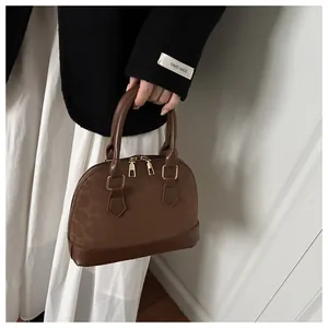 Detail of dark brown leopard print shell bag with smooth leather trim and gold zippers