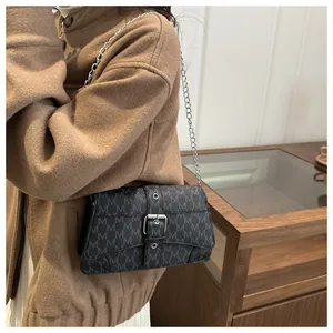 Detail view of printed monogram crossbody bag with silver buckle and metal chain strap