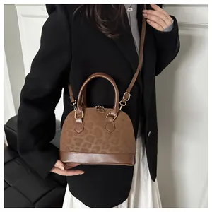 Detailed view of the leopard print patchwork shell bag worn with a black blazer outfit