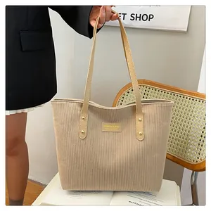 Detail of beige corduroy tote bag showing thick texture and brown faux leather straps