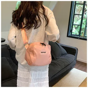 Pink nylon crossbody bag with a casual square design shown on a person in a soft cafe setting