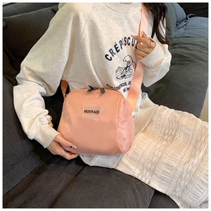 Pink nylon crossbody bag with adjustable strap and logo shown on a fashion model