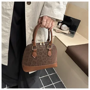Detail of leopard print shell bag with double zippers and sturdy brown handles