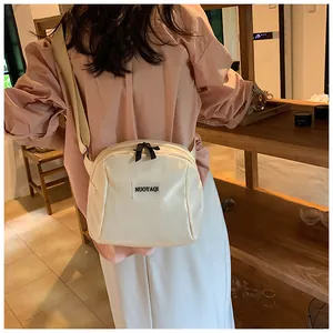 Detail view of cream white PU leather makeup bag with wide woven strap and dual zippers