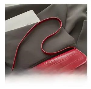Close-up of red crocodile texture bag with gold metal rotary lock and fine stitching