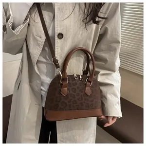 Brown leopard print shell bag with adjustable strap and top handles shown on model