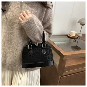 Detail of dark leopard print shell handbag with gold hardware in a cozy indoor setting