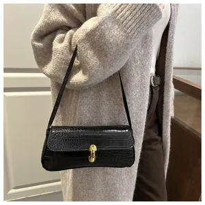 Detail of black faux crocodile texture underarm bag with gold oval metal buckle