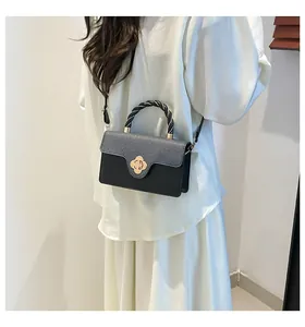 Détail du sac bandoulière bicolore avec fermoir trèfle et poignée tissée pour femme