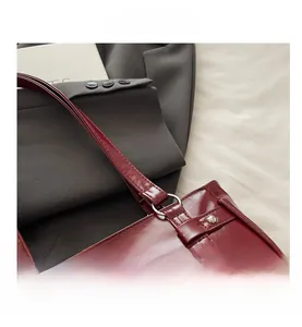Detail view of burgundy tote bag with metal rings, rivets, and white lace trim accents
