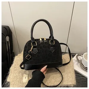 Close-up of black leopard embossed shell bag with gold zippers and adjustable strap